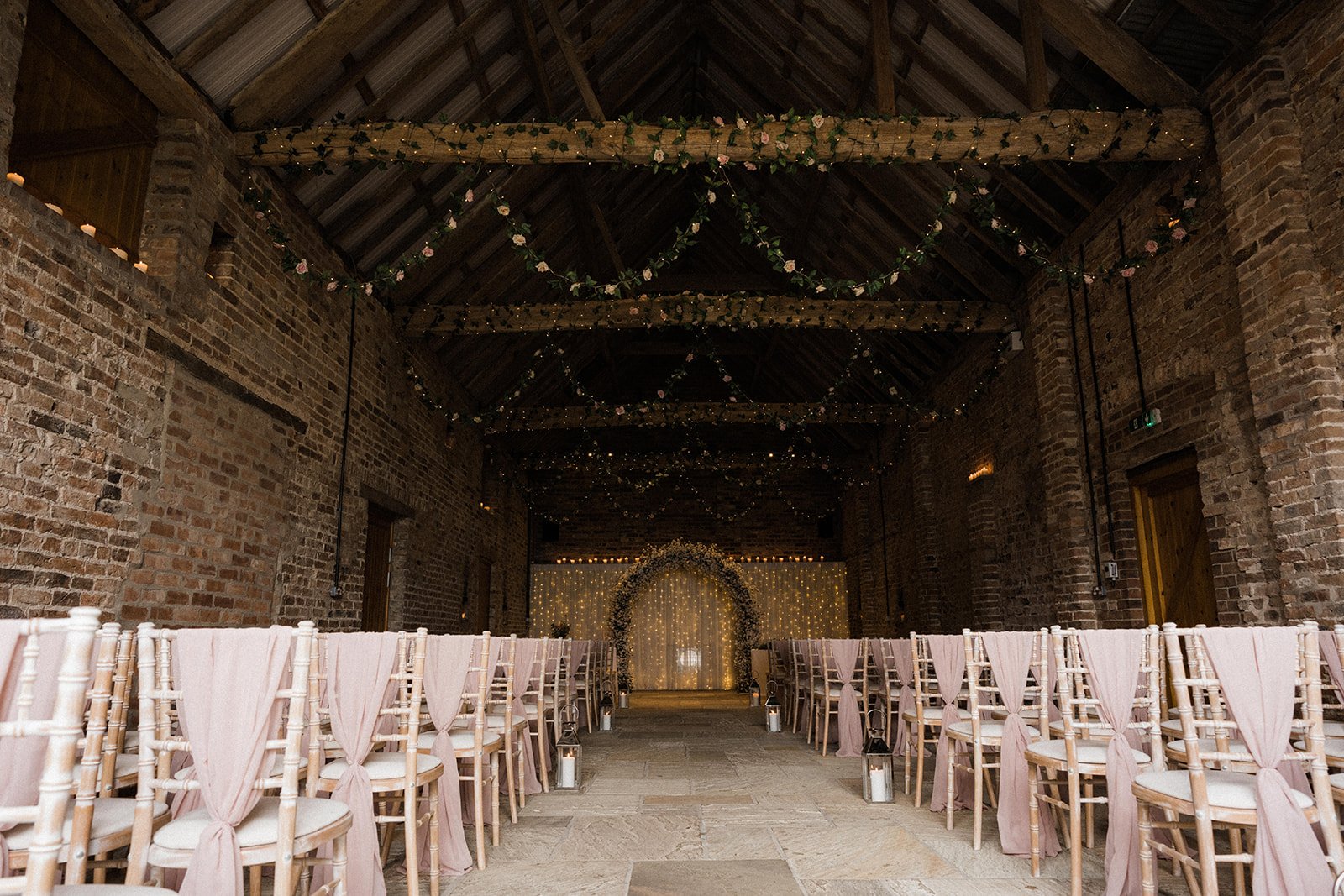 The Ceremony Barn set with draped chairs facing a floral moongate arch