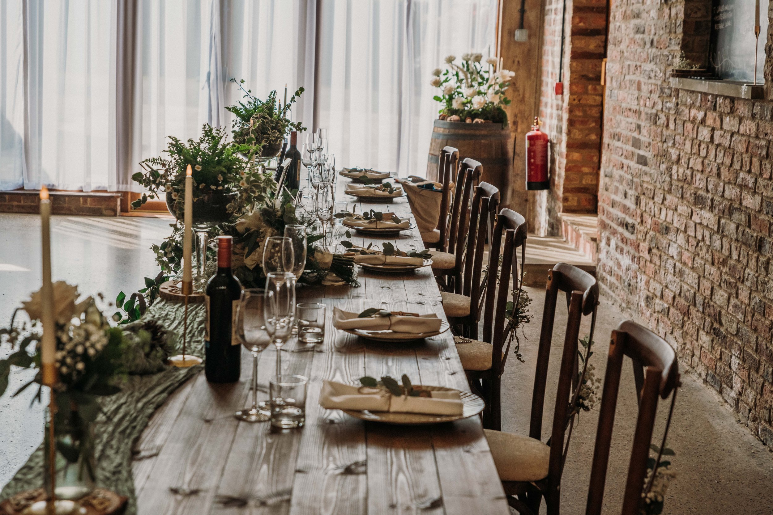 A long table set with greenery and candles in the Main Barn