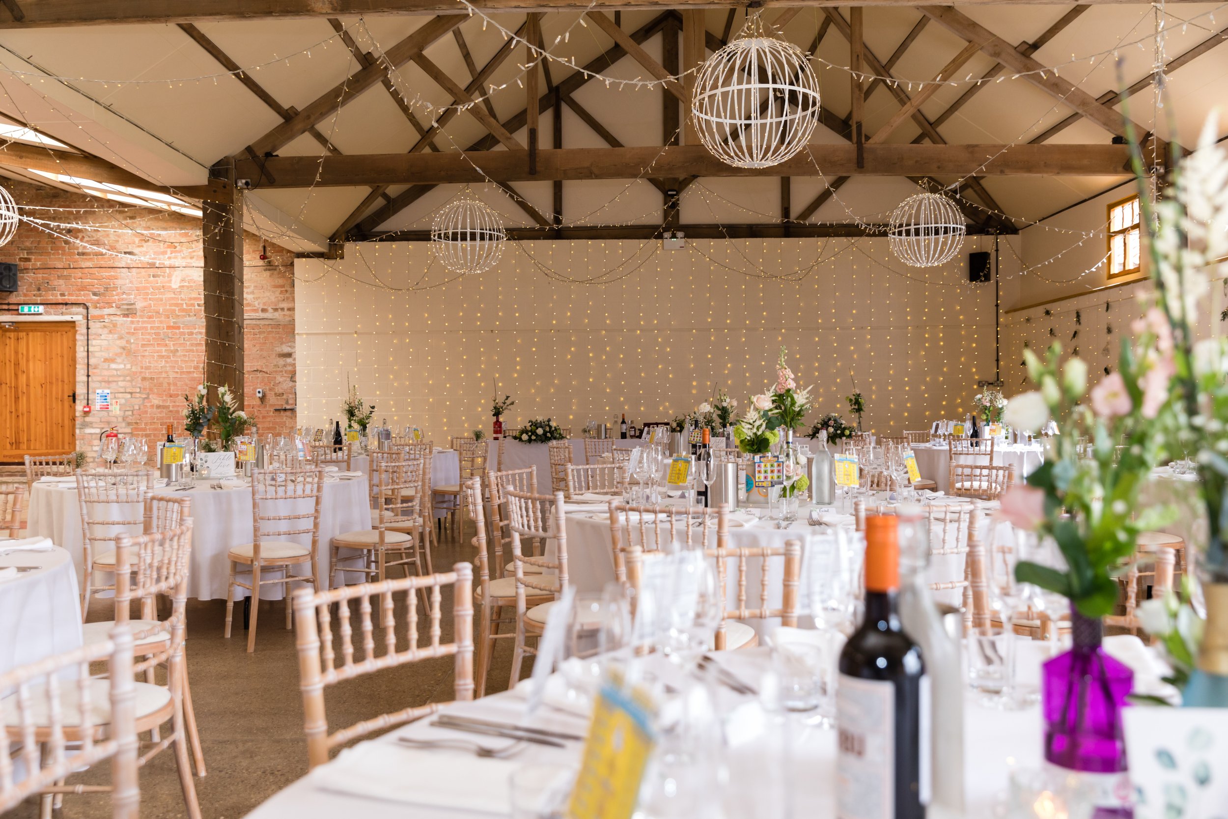 Round tables and florals under fairy lights in the Main Barn