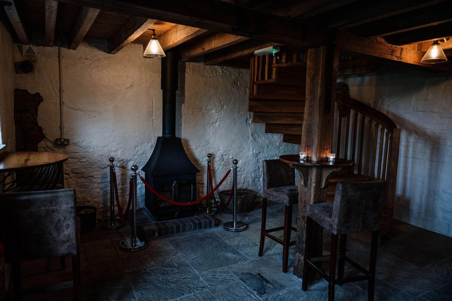 A lounge corner by the bar with a wood-burning stove and stone floor