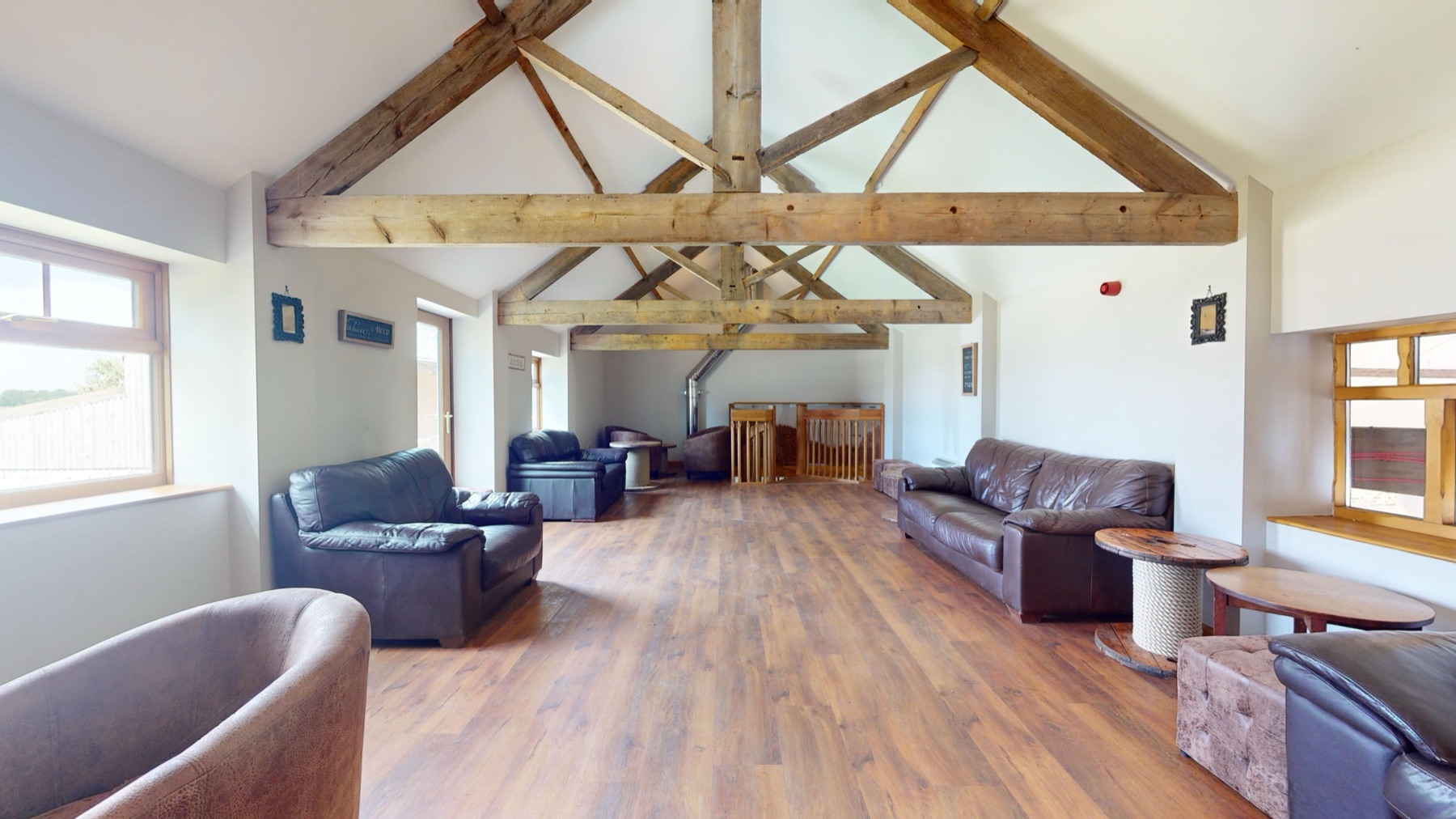 The Granary lounge under pale timber trusses, with leather sofas and countryside views