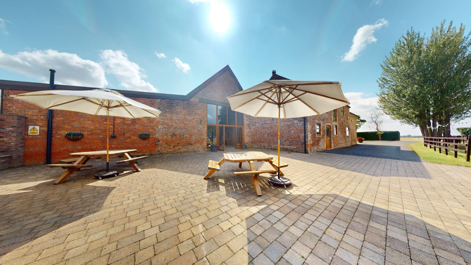 The Outside Barn courtyard in summer, with picnic benches and parasols