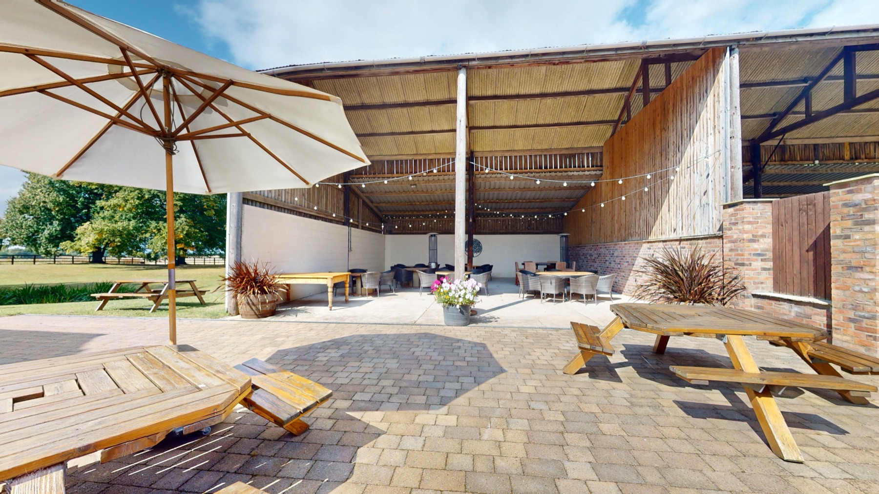 The covered Outside Barn open to the lawn, with festoon lights and rattan seating