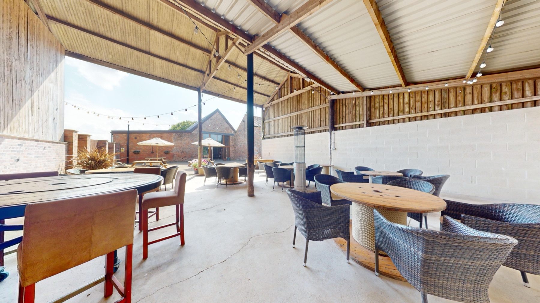Under the Outside Barn shelter, with rattan chairs and a patio heater