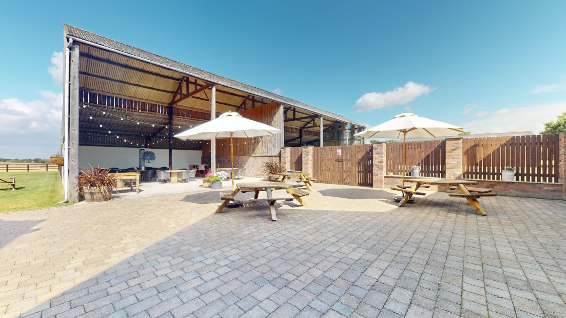 The Outside Barn and courtyard from the lawn, with parasols and seating